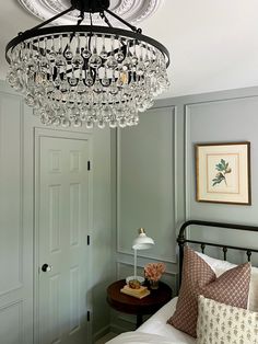 a chandelier hangs from the ceiling above a bed in a room with green walls