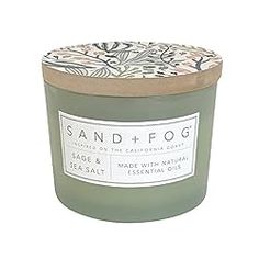 sand and fog candle in green glass with floral print on the lid, sitting on a white background