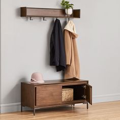 a coat rack with two coats hanging from it and a hat on the shelf next to it