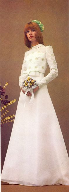 a woman in a white wedding dress with flowers on her head and hands behind her back