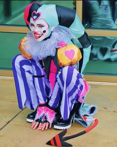 a clown sitting on the ground with his legs crossed