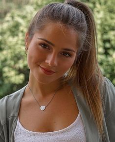 a young woman is smiling and wearing a necklace with a disc on it's neck