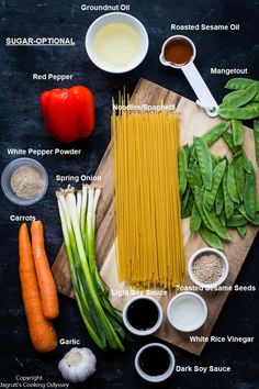 ingredients to make pasta laid out on a cutting board, including carrots, spinach, peppers, garlic, and flour