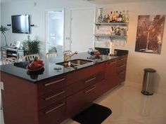 a kitchen with an island, sink and television on the wall