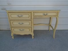 an old yellow desk with three drawers and one drawer on the bottom is sitting in front of a garage door