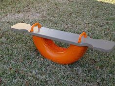 an orange tire swing in the grass with two handles on one end and another handle on the other side