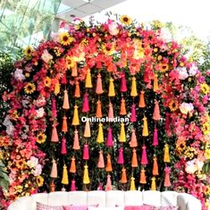 a white couch sitting in front of a wall covered with flowers and tassels