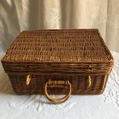 a large wicker basket with handles sitting on a white cloth covered tableclothed surface