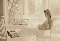 a pregnant woman sitting on a chair in front of a window