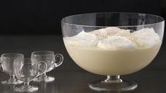 a bowl filled with pudding next to three glasses