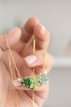 a woman holding onto a necklace with flowers on the front and back of her hand