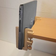 a dell laptop is attached to a wooden desk holder with one side open and the other side closed