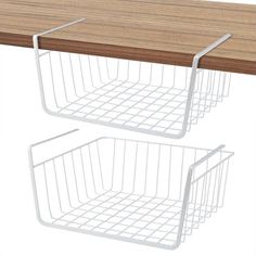 two white wire baskets sitting on top of a wooden table next to a brown counter