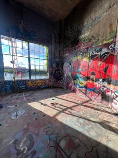 an empty room with graffiti all over the walls and windows on either side of it