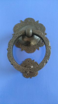 an old fashioned door handle on a blue wall with a metal ball in the center