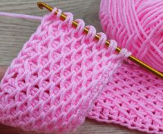 two balls of pink yarn next to each other with crochet hooks on them