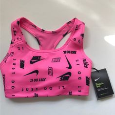 Brand New, Nike Swoosh Logo Printed Medium-Support Sports Bra In Size Xs. This Fun, Bright, Pink Sports Bra With Various Black Nike Logos/Slogans Has A Racerback Design And A Removable One-Piece Bra Pad. There’s A Bra Pad Pocket That Opens From The Top. It’s A Stretchy Fabric With Dri-Fit Technology That Helps Keep You Feeling Dry, Comfortable, And Supported. Never Been Worn, Comes New With Original Tags. Pink Sportswear For Light Sports, Pink Sporty Activewear For Light Sports, Pink Moisture-wicking Activewear For Sports Season, Sporty Pink Activewear For Light Sports, Pink Fitted Activewear For Light Sports, Fitted Pink Activewear For Light Sports, Fitted Pink Activewear For Sports, Pink Athletic Fit Racerback Sports Bra, Pink Racerback Sports Bra With Athletic Fit