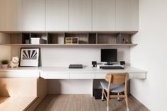 a desk with a chair and computer on it in a room that has white walls