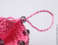 a pink crochet bag with beads hanging from it