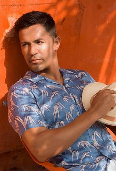 a man sitting on an orange chair with a hat in his hand and looking at the camera