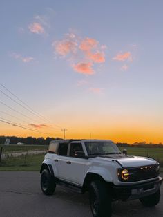 a white truck is parked on the side of the road at sunset or dawn with power lines in the background