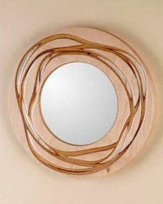 a round wooden mirror hanging on the wall above it's reflection, which is made out of wood strips