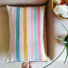 a person's feet are on the floor next to a pillow and some flowers