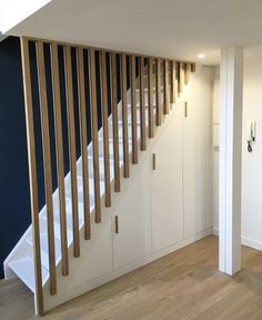 an empty room with white walls and wooden railings on the wall, next to a stair case