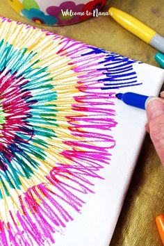 someone is drawing on a canvas with crayons and colored pencils in front of them