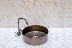 a sink with a faucet on top of it next to a marble counter