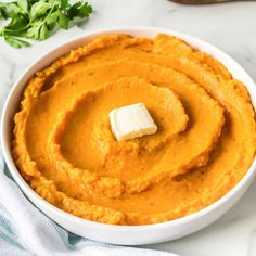 a white bowl filled with mashed sweet potatoes and topped with a pate of butter