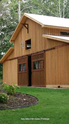 a large wooden barn sitting on top of a lush green field