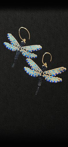 a pair of earrings with blue and white beads hanging from it's hooks on a black background