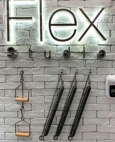 a sign that says flex hanging from the side of a brick wall next to some hooks