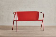 a red chair sitting on top of a hard wood floor next to a white wall