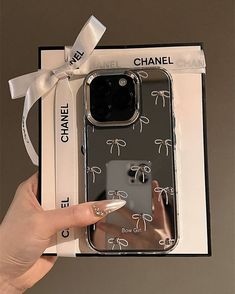 a person holding up a cell phone case in a box with bows on the front