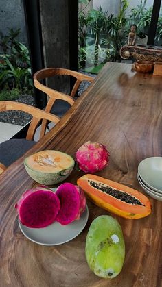 the table is set with different fruits and vegetables on it, including papaya, kiwi, dragon fruit