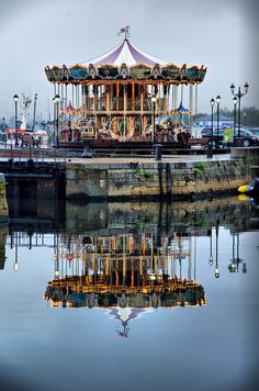 a merry go round sits in the middle of a body of water next to a dock