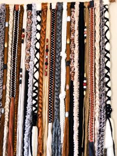 a bunch of braids hanging on a wall next to each other in different colors