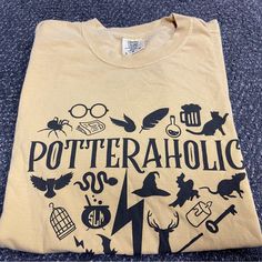 a t - shirt that says potteraholic on the front, and various symbols around it