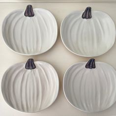 four white pumpkin shaped plates with black handles