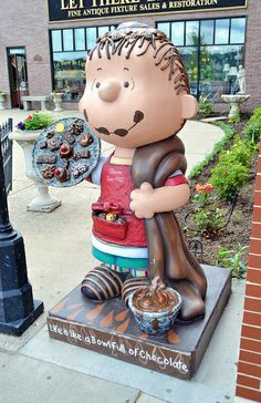 a statue of a man holding a bowl of food in front of a storefront