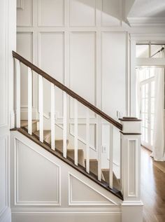 an empty room with wood floors and white walls, along with a wooden banister