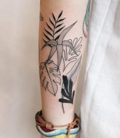 a person with a tattoo on their arm has a plant and leaves in the background