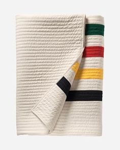 a white quilted blanket with multi - colored stripes