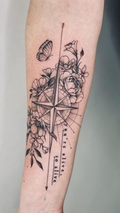 a compass and flowers tattoo on the right arm, with an arrow in the middle