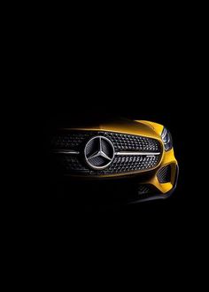 the front end of a yellow mercedes sports car on a black background with its hood up