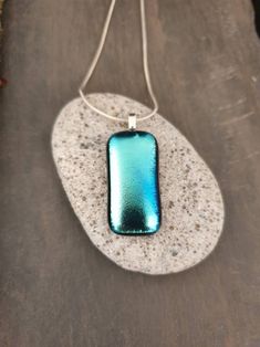 a blue pendant is sitting on a rock