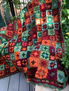 a blanket that is sitting on top of a wooden floor next to a potted plant