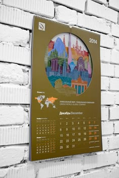 a calendar hanging on a brick wall with a cityscape in the middle and numbers below it